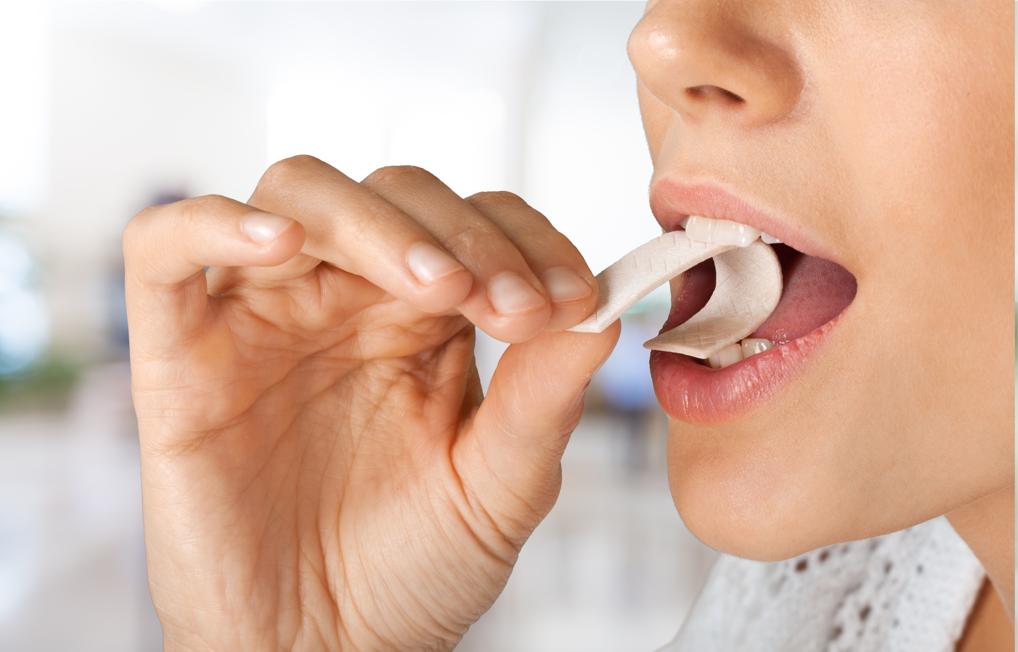 woman placing a piece of gum in her mouth